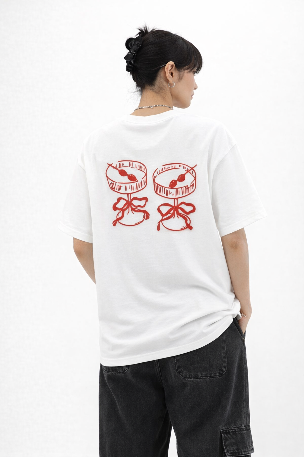 Person wearing a white t-shirt with red graphics on the back, standing against a white background