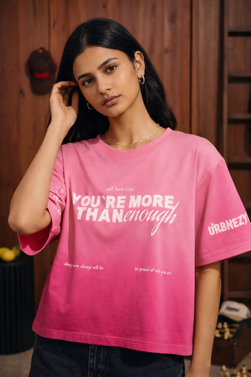 Woman wearing a pink t-shirt with a motivational message indoors.