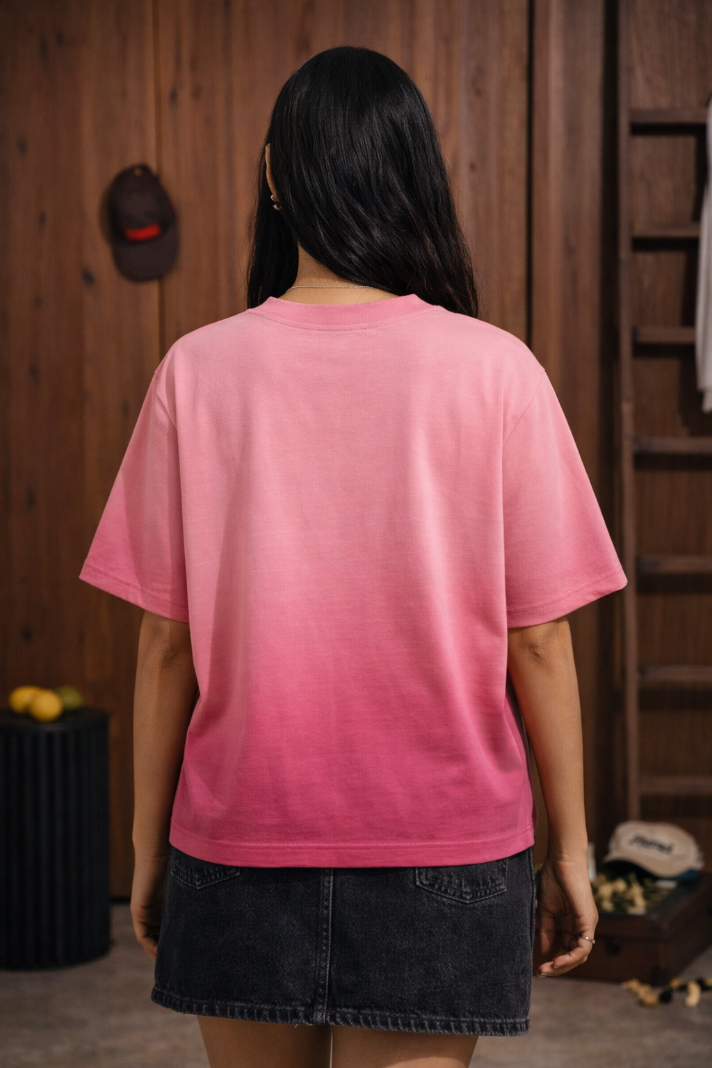 Person wearing a pink ombre t-shirt with a wooden wall background